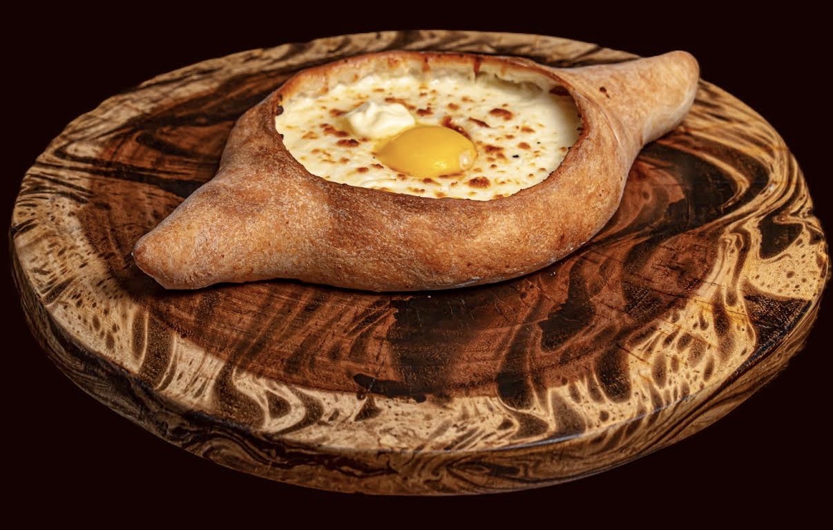 Adjarian khachapuri with egg yolk on a wooden serving board